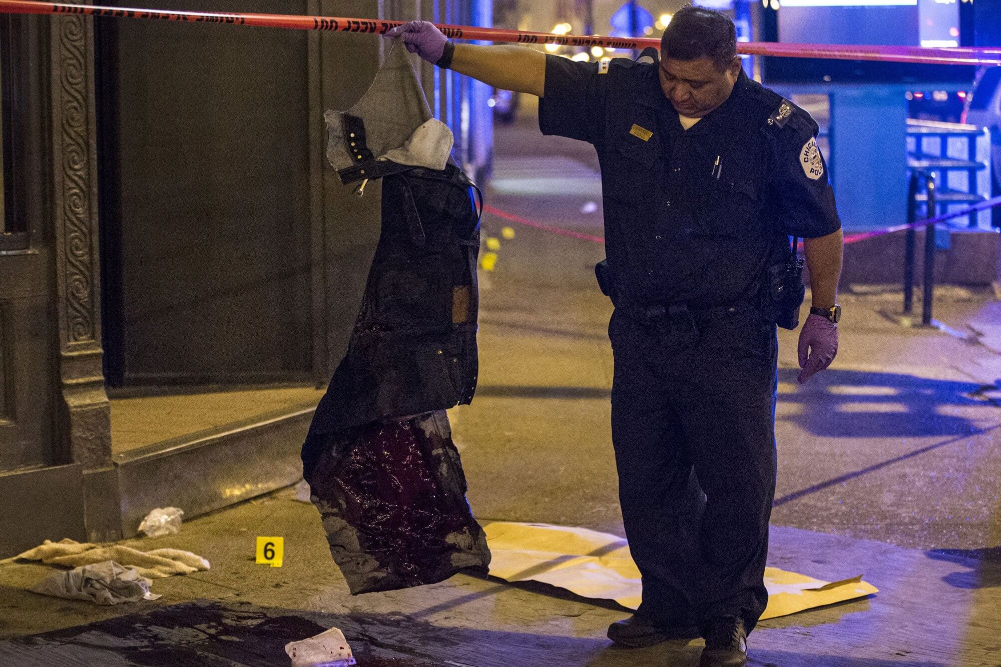 A police officer in Chicago, Illinois inspects bloody clothing belonging to a gunshot victim.