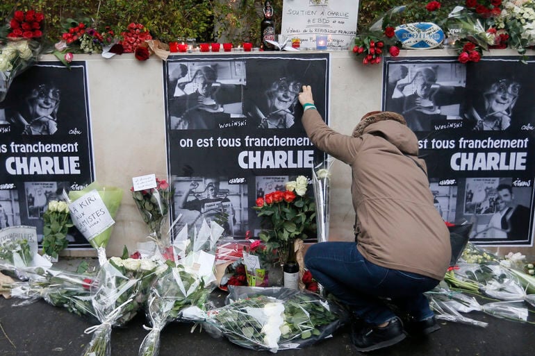 A mourner adds flowers to a Charlie Hebdo memorial as photographed in January 2015 by Gonzalo Fuentes via Reuters.
