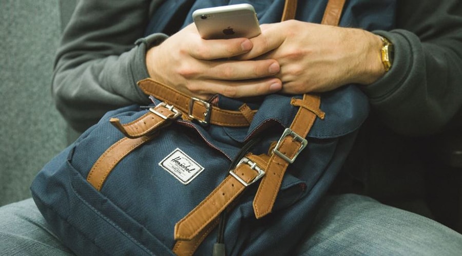 Man using phone holding backpack