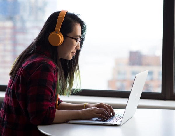 girl listening to headphones while writing