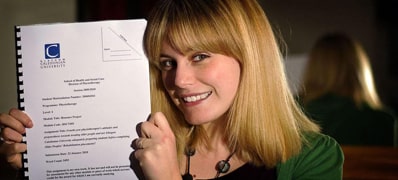 Woman proudly holding up a dissertation.